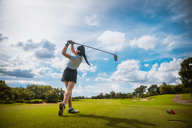 a female golfer hits the ball with her bat