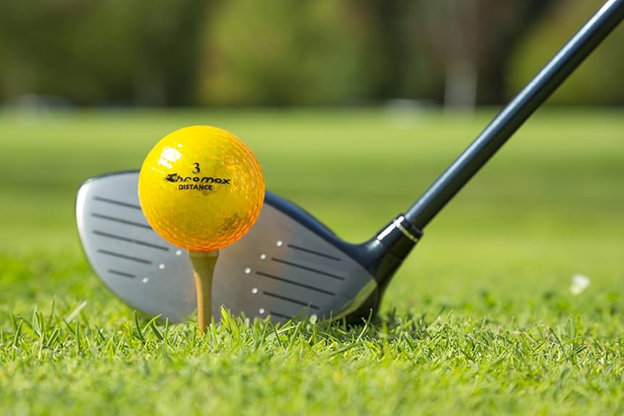 An orange golf balls and golf bats in golf course