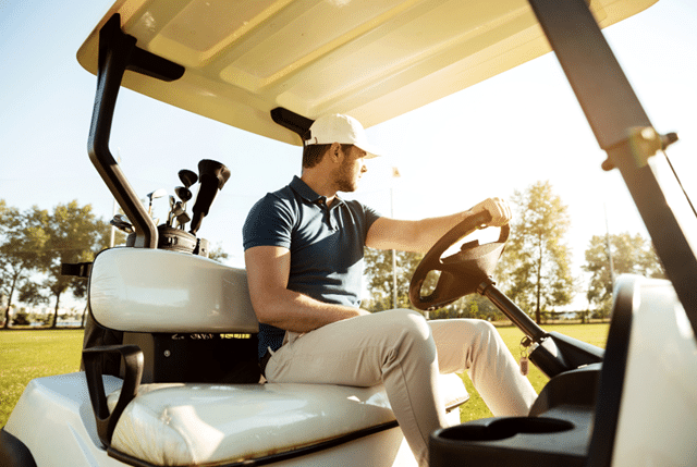 a golfer is driving golf cart with golf cart bag in the back of the golf cart