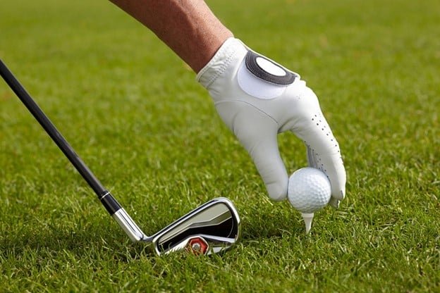 a white golf ball, golf ball, golf gloves in a green golf course