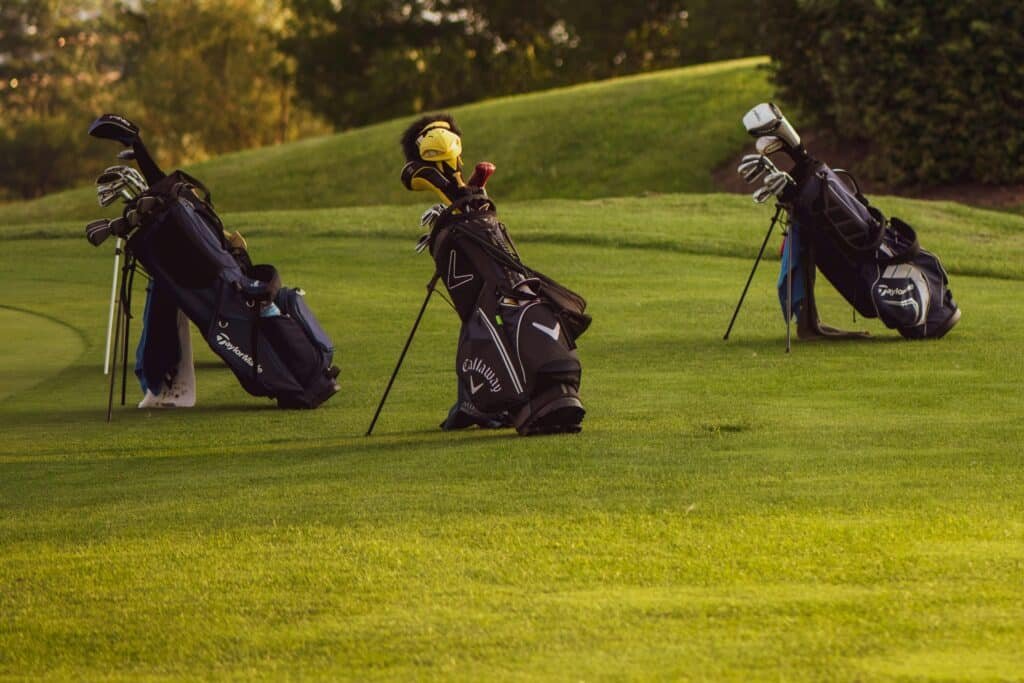Set of golf bags on a sunlit golf course ready for a game.